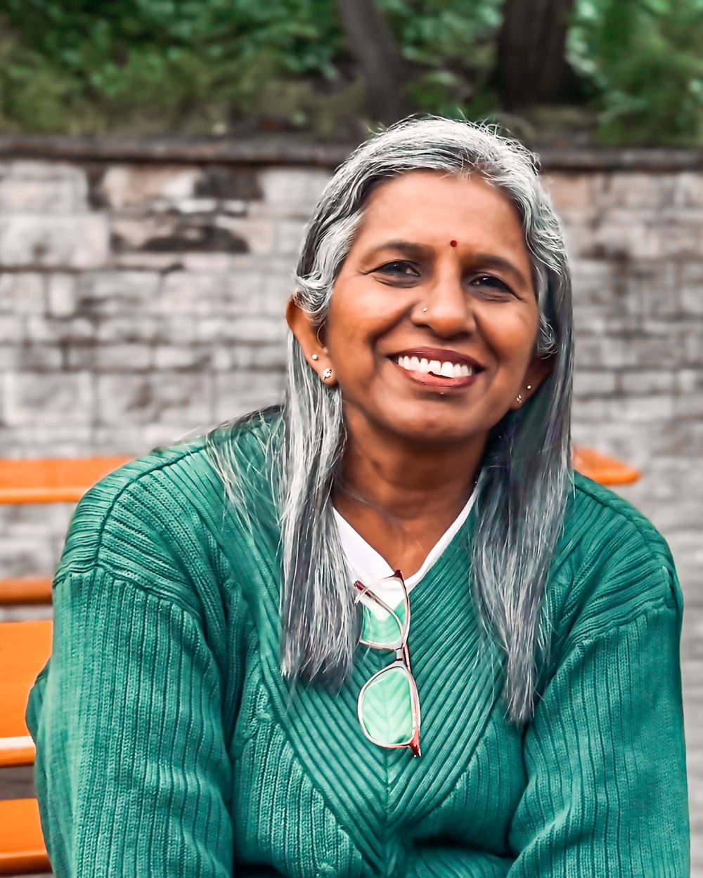 Sashirekha Natarajan smiling, in a green sweater, seated outdoors